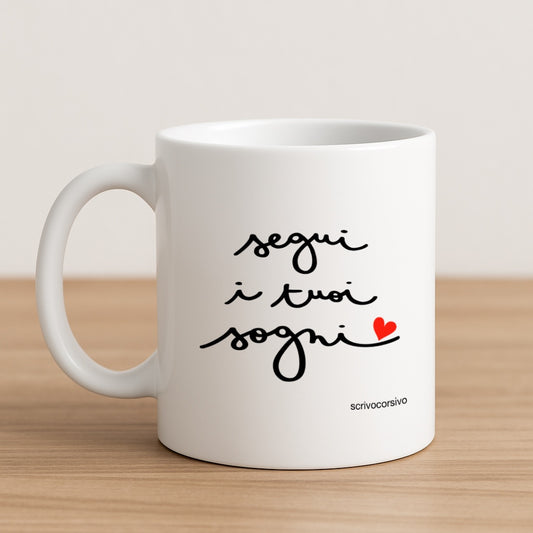 tazza mug calligrafata con la frase "segui i tuoi sogni" scritta a mano in corsivo nero con un piccolo cuore rosso