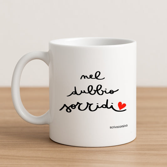 tazza mug calligrafata con la frase "nel dubbio sorridi” scritta a mano in corsivo nero con un piccolo cuore rosso