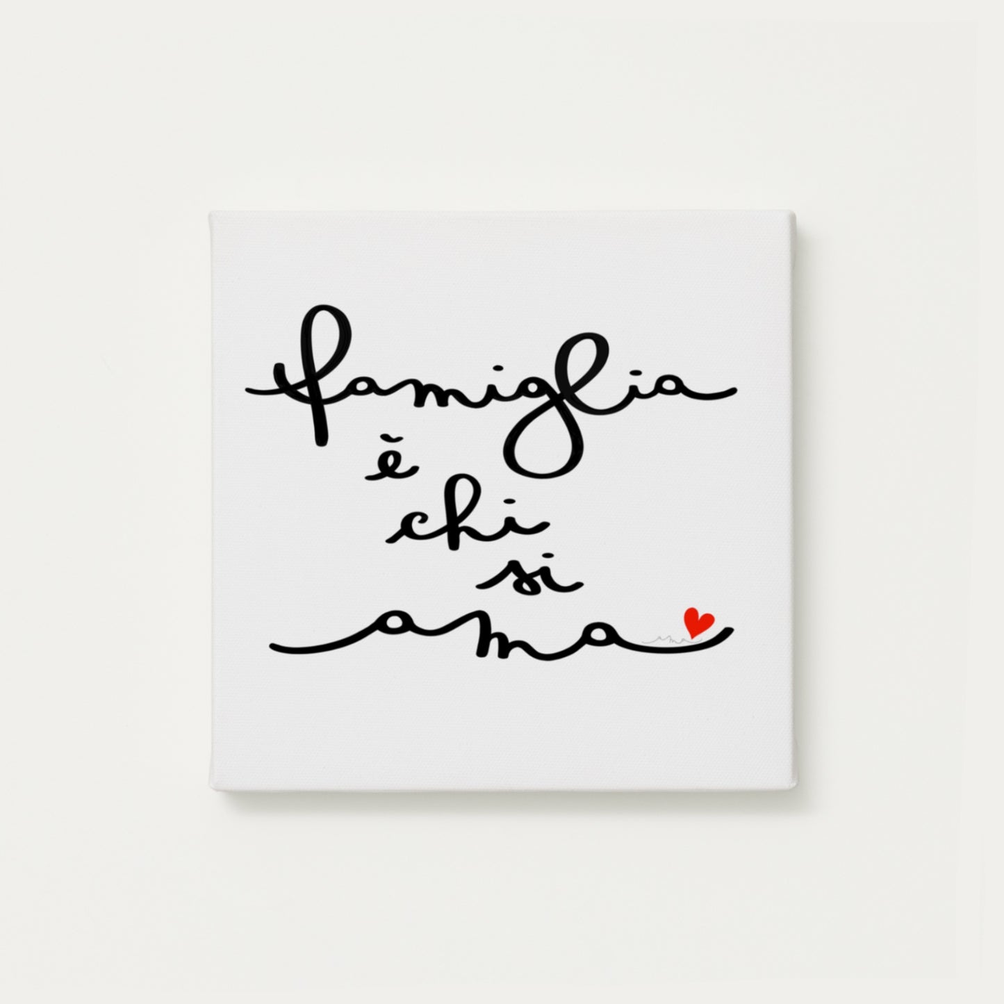 tela calligrafata con la scritta “famiglia è chi si ama” scritta a mano in corsivo nero con un piccolo cuore rosso - formato quadrato cm 30x30