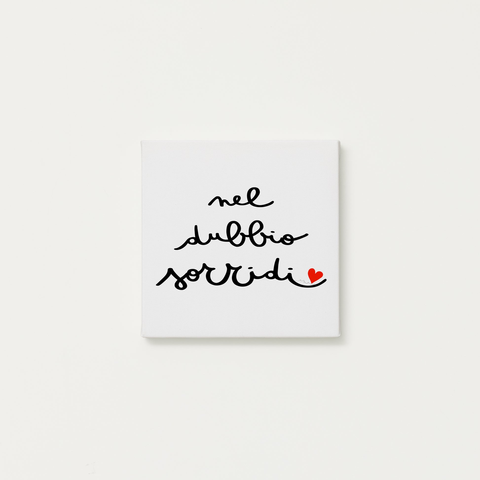 tela calligrafata con la scritta “nel dubbio sorridi” scritta a mano in corsivo nero con un piccolo cuore rosso - formato quadrato cm 20x20