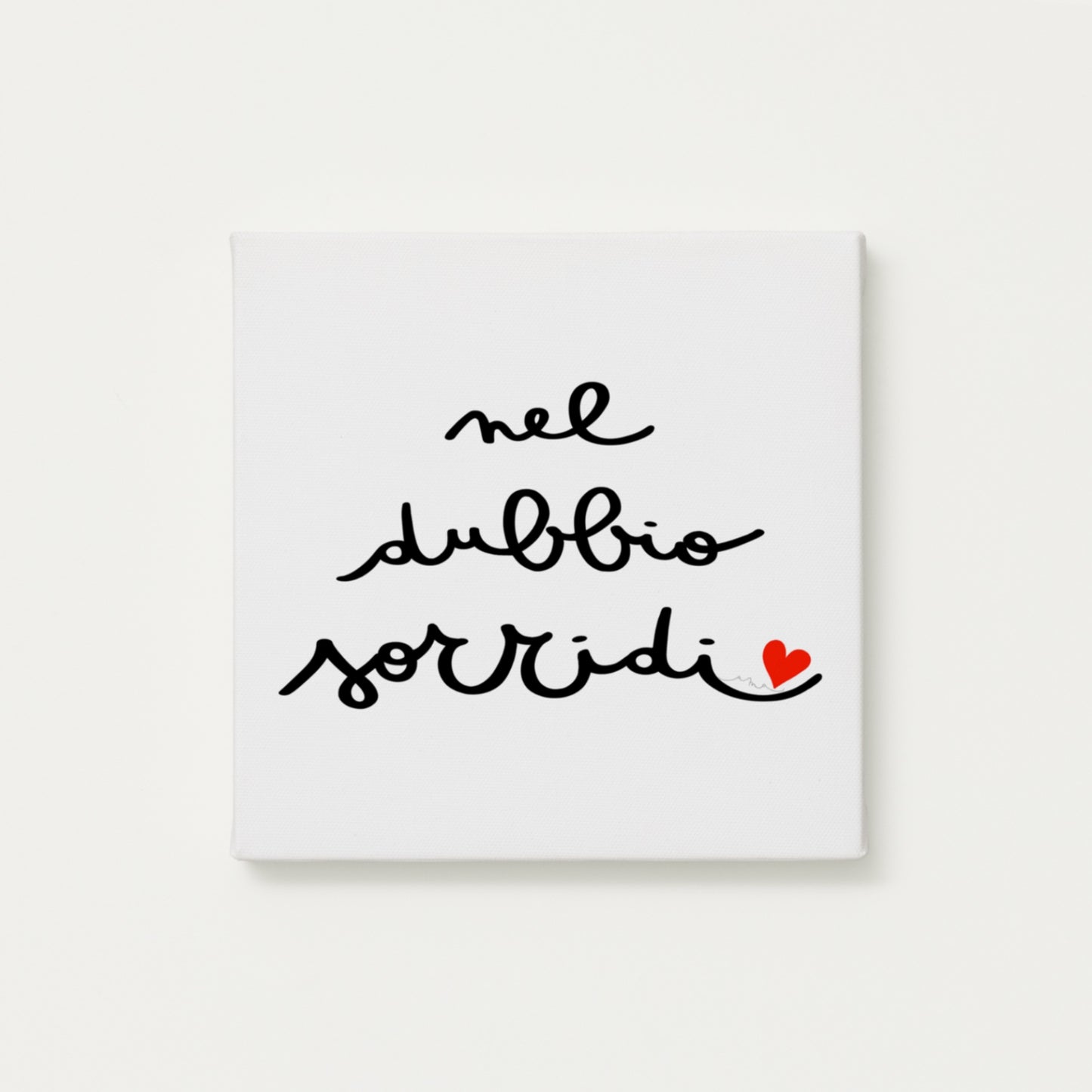 tela calligrafata con la scritta “nel dubbio sorridi” scritta a mano in corsivo nero con un piccolo cuore rosso - formato quadrato cm 30x30